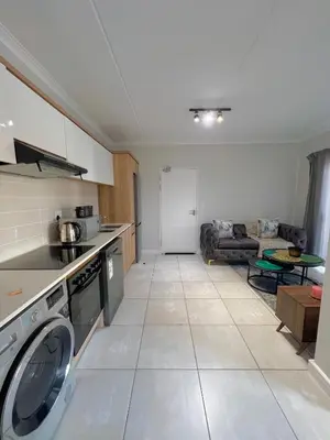 a kitchen with a washer and a living room at Blyde Lagoon in Pretoria