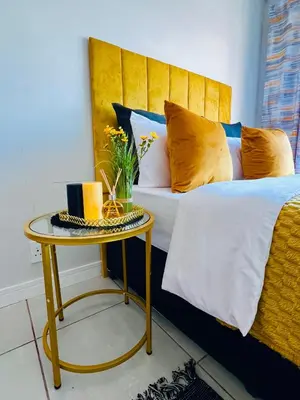 a bed with a yellow headboard and a table at Blyde Lagoon in Pretoria