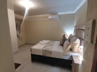 a bedroom with a bed with pillows on it at The Glenwood RRR Guesthouse in Midrand