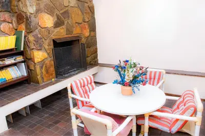a table and chairs in front of a stone fireplace at The Glenwood RRR Guesthouse in Midrand