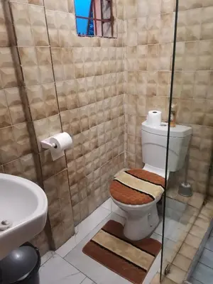 a bathroom with a toilet with a glass shower at The Glenwood RRR Guesthouse in Midrand