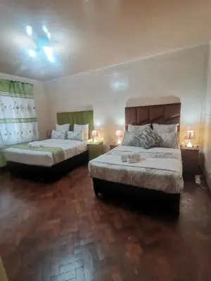 a bedroom with two beds and two lamps in it at The Glenwood RRR Guesthouse in Midrand
