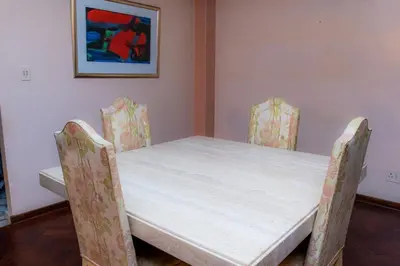 a table and chairs in a room with a painting at The Glenwood RRR Guesthouse in Midrand