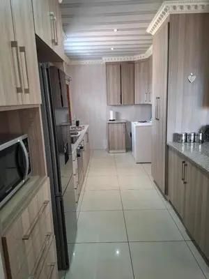 a large kitchen with wooden cabinets and white appliances at Entire Modern House!!- Middelburg in Middelburg