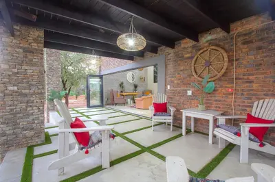 a patio with chairs and tables and a brick wall at Edjami River View in Marloth Park