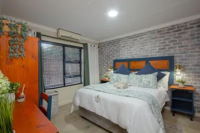 a bedroom with a large bed and a brick wall at Edjami River View in Marloth Park