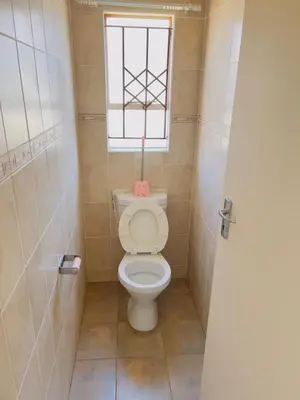 a small bathroom with a toilet with a window at Private Suite in Polokwane
