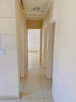 an empty hallway with white walls and a white tile floor at Private Suite in Polokwane