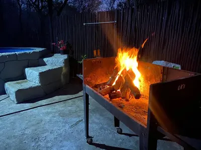 a fire in a grill in a backyard at night at Kettie&Klip Self Catering Accommodation in Marloth Park