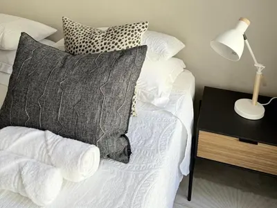 a bed with a pillow and a lamp on a table at Whispering Thorns Off-Site Apartment in White River
