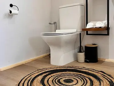 a bathroom with a white toilet and a rug at Whispering Thorns Off-Site Apartment in White River