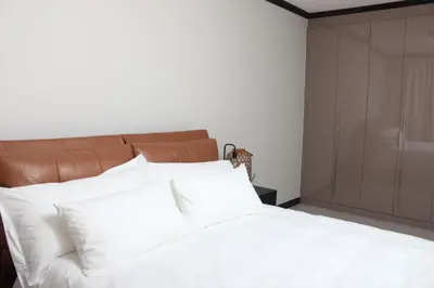 a bedroom with a white bed and a brown cabinet at Blue Lake Estate Home in Midrand