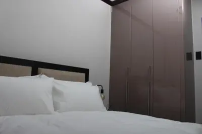 a bedroom with a bed with white pillows and a closet at Blue Lake Estate Home in Midrand