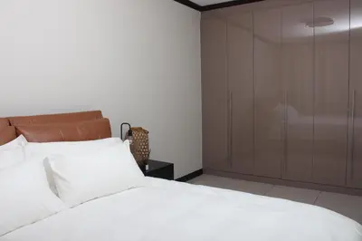 a bedroom with a white bed and a glass closet at Blue Lake Estate Home in Midrand