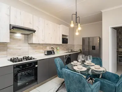 a kitchen with a glass table and blue chairs at Reece Luxury Midrand Suite in Midrand