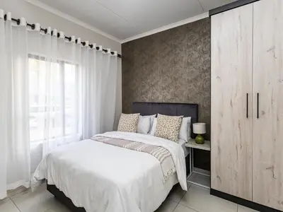 a bedroom with a large white bed and a cabinet at Reece Luxury Midrand Suite in Midrand