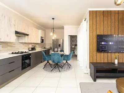 a kitchen with a table and blue chairs in it at Reece Luxury Midrand Suite in Midrand