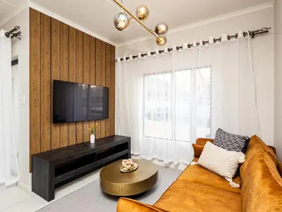 a living room with a couch and a tv at Reece Luxury Midrand Suite in Midrand