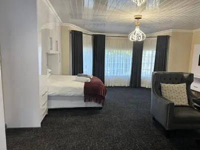 a bedroom with a bed and a chair and a chandelier at Tranquil view lodge in Haenertsburg