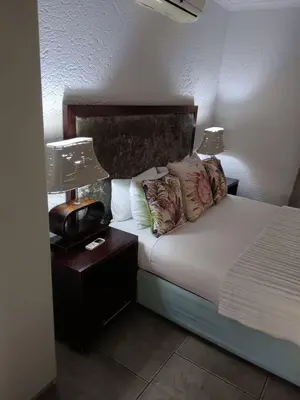a hotel room with a bed with a phone on a table at Zamabhele Properties in Nelspruit