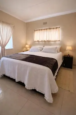 a bedroom with a large white bed with a window at Meadway on the parks in Benoni