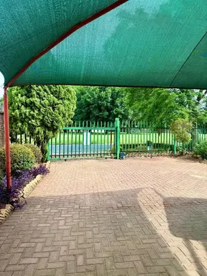 a green fence in front of a brick patio at Cosy retreat for 2 at MeadWay in Benoni