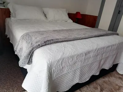 a bed with a white comforter and pillows at Cosy retreat for 2 at MeadWay in Benoni
