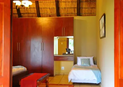 a room with a bedroom with a bed and a mirror at Palmwag Tzaneen in Tzaneen