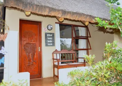 a small house with a thatch roof and a door at Palmwag Tzaneen in Tzaneen