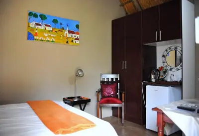 a bedroom with a bed and a table and a chair at Palmwag Tzaneen in Tzaneen