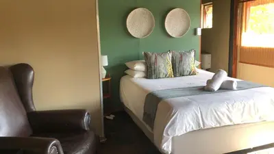 a bedroom with a bed with a chair and two mirrors at Palmwag Tzaneen in Tzaneen