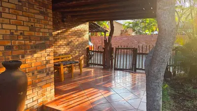 a patio with a brick wall and a tree at Dika Dika Den in Phalaborwa