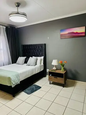 a bedroom with a bed and a table with a lamp at SerenityStay 37 on Zebra in Polokwane