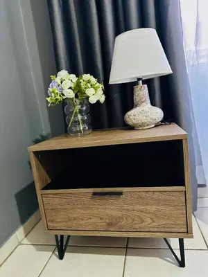 a night stand with a lamp and flowers on it at SerenityStay 37 on Zebra in Polokwane