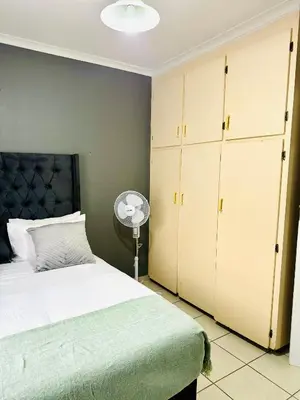 a bedroom with a bed and cabinets and a fan at SerenityStay 37 on Zebra in Polokwane