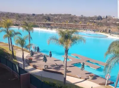 a large swimming pool with palm trees in front of it at The Corinthians in Pretoria
