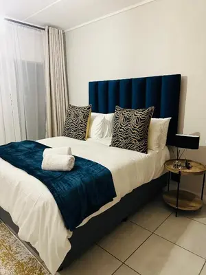 a bedroom with a large bed with a blue headboard at The Corinthians in Pretoria