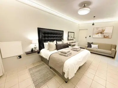 a bedroom with a large bed and a living room at Blanche Guesthouse in Pretoria
