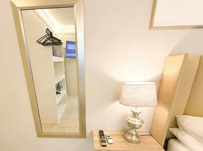 a bedroom with a mirror and a lamp on a table at Blanche Guesthouse in Pretoria