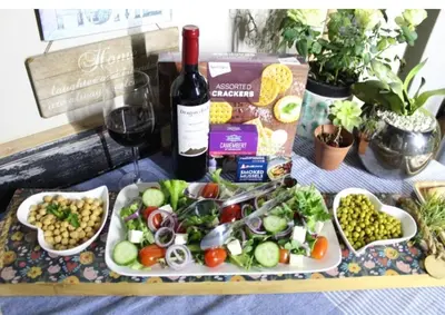 a table with a plate of food and a bottle of wine at Rose Vintage Cottage in Pretoria
