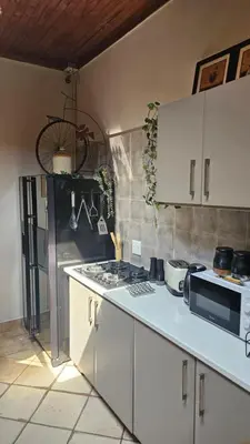 a kitchen with white cabinets and a stove top oven at Rose Vintage Cottage in Pretoria