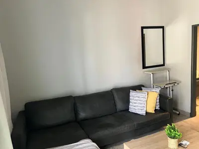 a black couch in a living room with a mirror at Circa 43 1 Bedroom Lynwood in Pretoria