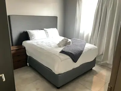 a bed with white sheets and pillows in a bedroom at Circa 43 1 Bedroom Lynwood in Pretoria