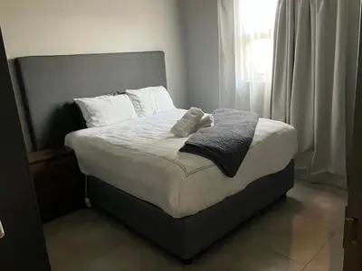 a bed with white pillows and gray towels on it at Circa 43 1 Bedroom Lynwood in Pretoria