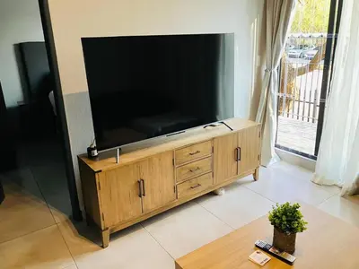 a large flat screen tv sitting on a wooden entertainment center at Circa 43 1 Bedroom Lynwood in Pretoria