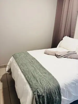 a bed with a green blanket on top of it at MamelaniQhibi Luxary Apartment in Nelspruit