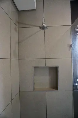 a shower with a tile wall with a glass door at MamelaniQhibi Luxary Apartment in Nelspruit
