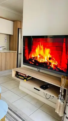 a flat screen tv sitting on a stand with a fireplace at Cozy abode in Pretoria