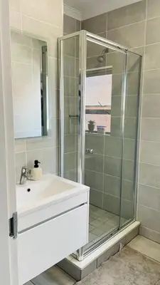 a bathroom with a glass shower and a sink at Cozy abode in Pretoria