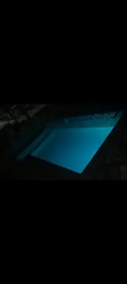 a blue swimming pool in a dark room at The Hope Apartments in Nelspruit